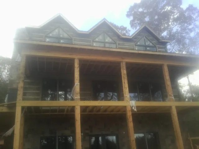 Dormers and porch framing on a large log home under construction — Roof Coating work by our crew in Rexford