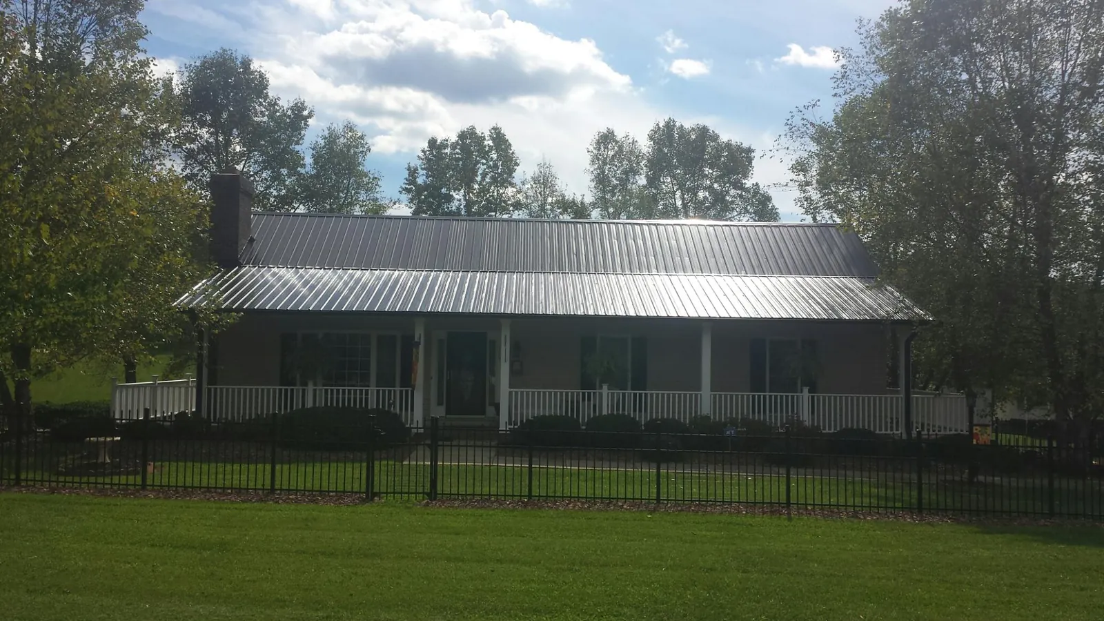 Gray metal roof on a brick ranch with a full width front porch — Gutter Guard Installation work by our crew in Rexford
