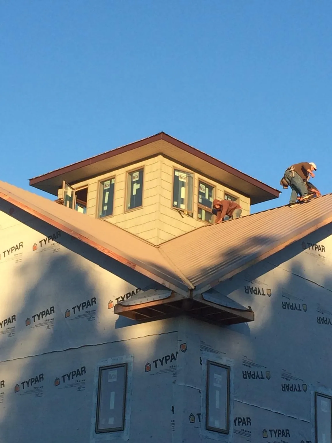 Roofers working around a rooftop cupola on a new metal roof at sunset — Roof Waterproofing in Rexford by Roofing Brothers
